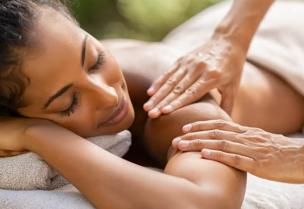 a woman lying on a towel with her hands on her shoulder